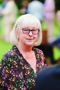 Anna Teng, former staff member of Gray's Inn, poses for a picture, she is wearing glasses and has her hair down. She is wearing a floral patterened v-neck dress.