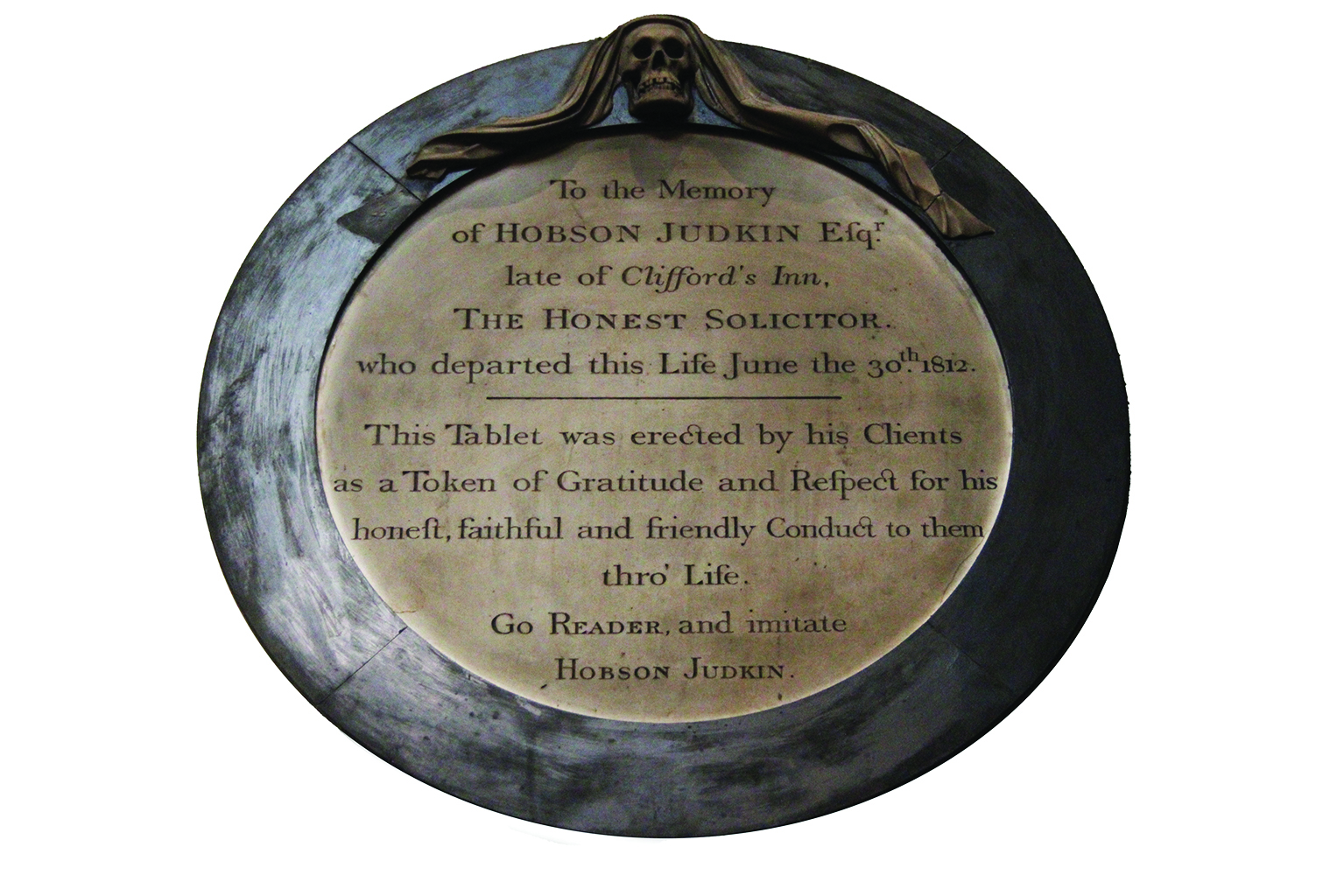 Bronze memorial plaque with an inscription for Hobson Judkin, featuring a skull detail at the top. The tone is respectful and commemorative.