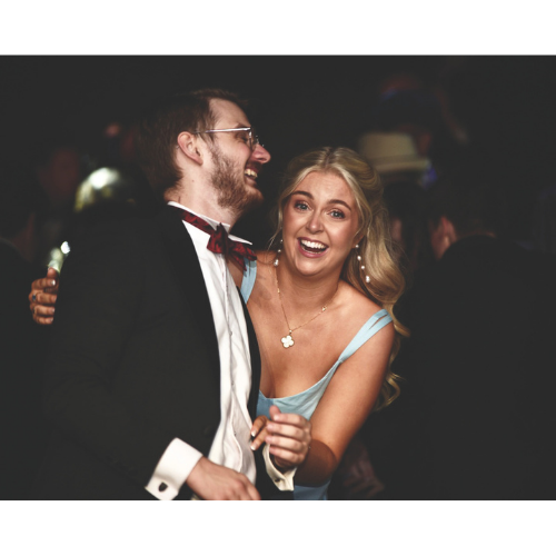 Two people dancing. The man on the left wears a suit and bow-tie. The woman on the right wears a light blue dress.